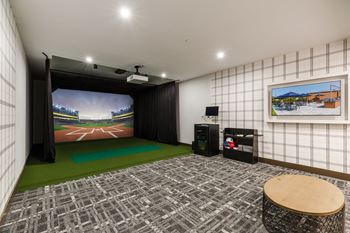 A living room with a large screen tv and a green rug